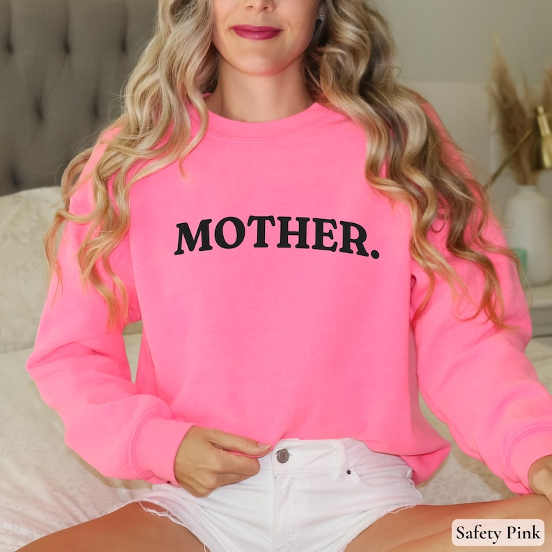 Womans safety pink colored sweatshirt with black text that says Mother in arched text across the upper chest