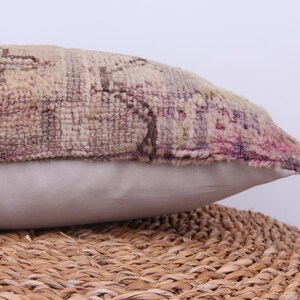 Puede incluir: Una almohada decorativa con una funda de tela estampada en beige, rosa y marr&oacute;n. La almohada tiene un respaldo blanco de algod&oacute;n y est&aacute; sentada sobre una superficie de mimbre tejido.