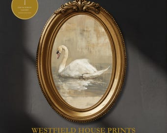 May include: An oval gold-toned frame containing a painting of a white swan swimming on water. The frame features ornate detailing at the top. A circular logo with a dragonfly icon and the text THE VICTORIAN GALLERY is visible. WESTFIELD HOUSE PRINTS.