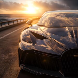 May include: A black sports car with a carbon fibre finish is parked on a coastal road. The car's hood and front grill are visible, reflecting the golden light of a sunset over the sea. The car's design is aerodynamic and modern.