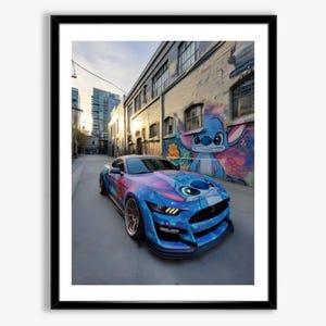 May include: Framed print of a blue sports car with a custom wrap featuring a galaxy design and a cartoon character. The car is parked on a city street, with a mural of the cartoon character on a brick wall.
