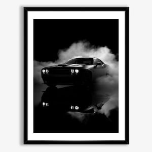 May include: Black and white framed print of a muscle car, surrounded by smoke. The car's headlights are illuminated, and its reflection is visible below. The image is set against a dark background, creating a dramatic effect.