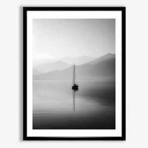 May include: Black and white framed print of a sailboat on calm water, with mountains in the background. The sailboat's reflection mirrors in the water. The image has a serene, minimalist aesthetic.