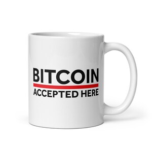 May include: White ceramic mug with a black and red design that says "BITCOIN ACCEPTED HERE".