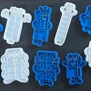 May include: A collection of blue and white plastic cookie cutters in various shapes, each resembling a cartoon character. The cutters are designed with distinct facial features and body shapes, perfect for creating themed cookies.