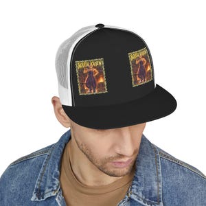 Op de afbeelding: Een zwart-witte truckerpet met een platte klep en een achterkant van mesh. Het voorpaneel toont twee identieke rechthoekige grafische prints van een personage uit Jujutsu Kaisen in een vurige omgeving met gele tekst.