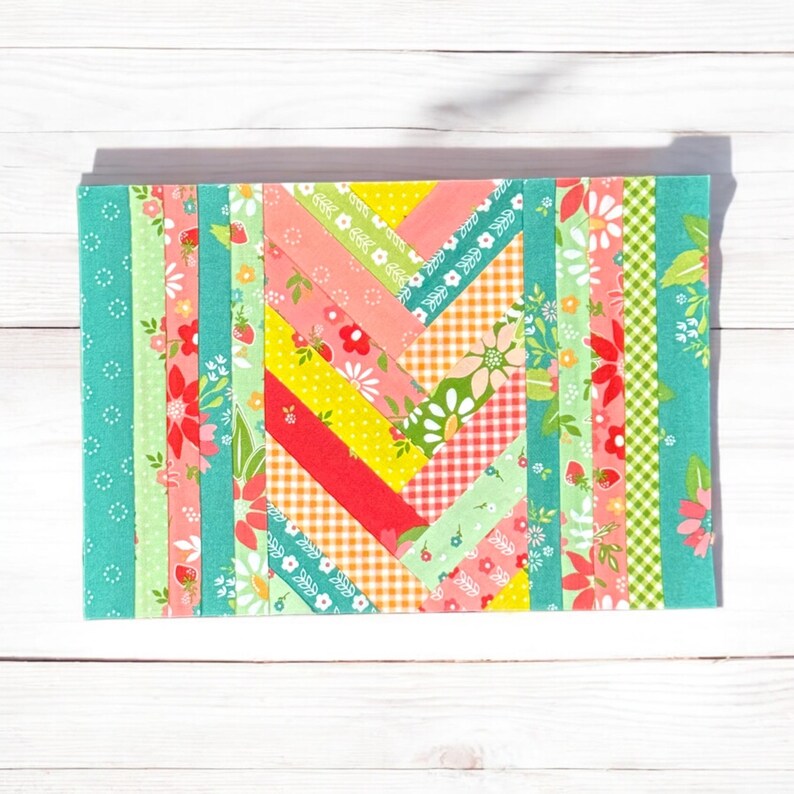 Pu&ograve; includere: Un blocco di trapunta patchwork colorato con un motivo a chevron. Il blocco &egrave; composto da strisce di tessuto in varie tonalit&agrave; di verde, rosa, giallo e rosso. Il tessuto presenta motivi floreali e geometrici.