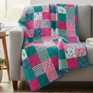 May include: A patchwork quilt featuring a repeating grid of square fabric panels in shades of teal, magenta, and white. The design includes solid colors, floral patterns, and thin horizontal stripes, all stitched together with a quilted texture.