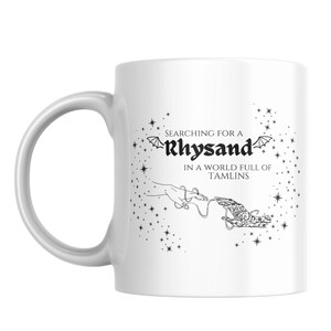 May include: White ceramic mug with a black and white graphic design. The design features a hand reaching out with a string attached to another hand. The text reads "Searching for a Rhysand in a world full of Tamlins".