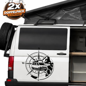 Könnte beinhalten: Weißer Campingbus mit einem schwarz-weißen Kompassrosen-Aufkleber an der Seite. Der Aufkleber zeigt eine Illustration eines Campingbusses, eine Karte und Richtungspfeile. Der Bus hat ein Ersatzrad hinten und ein Aufstelldach. Das Bild enthält einen Aufkleber mit der Aufschrift "2X DOPPELPACK - 2 AUFKLEBER".