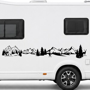May include: A black vinyl decal applied to the side of a white recreational vehicle. The design features a continuous landscape silhouette including jagged mountain peaks, dense pine forests, a lone hiker with a walking stick, and two deer.