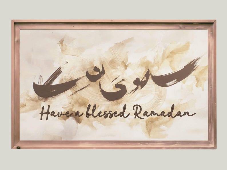 May include: A framed print with a beige background and brown brushstrokes. The Arabic word for Ramadan is written in brown calligraphy. The text "Have a blessed Ramadan" is written in brown below the calligraphy.