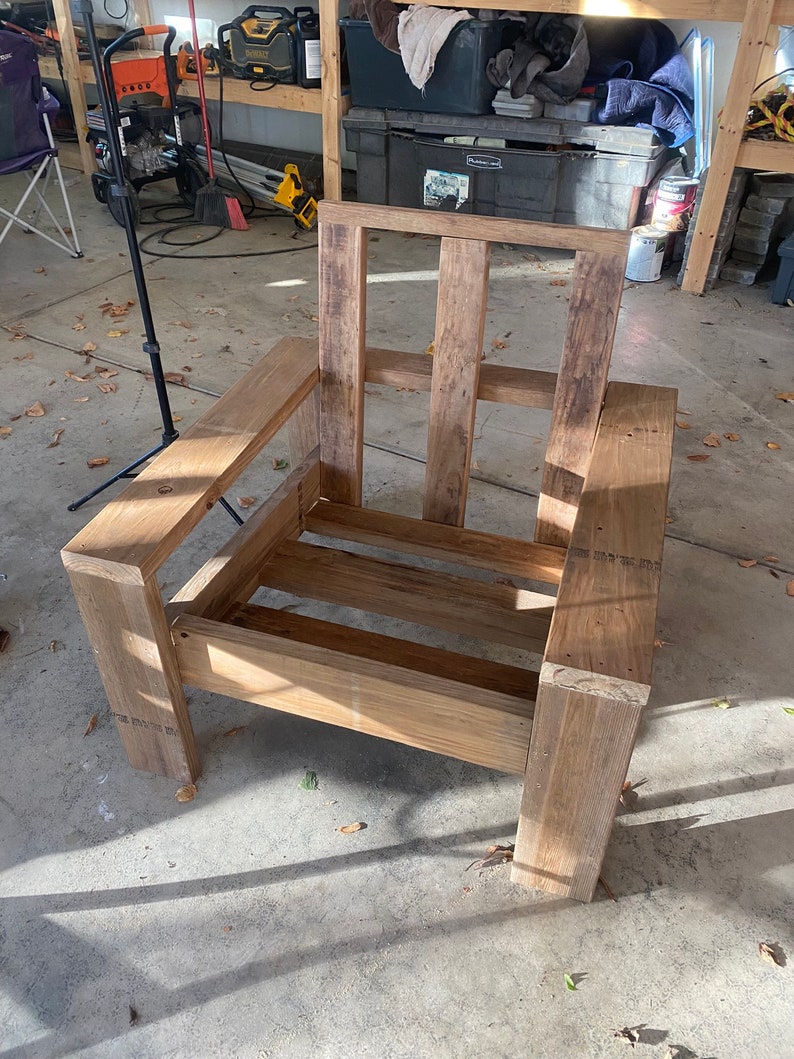 Puede incluir: Un marco de silla de madera con un acabado de madera natural. La silla tiene un dise&ntilde;o simple con un asiento y un respaldo rectangulares.
