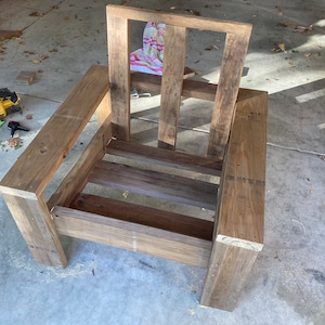 Puede incluir: Un marco de silla de madera con respaldo y asiento de listones. La silla est&aacute; sin terminar y tiene un color de madera natural.
