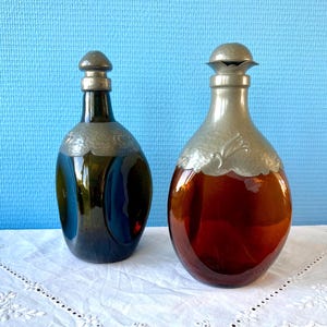 Två triangulära Art Deco-whiskykaraffer i bärnsten av Georg Nilsson med Zeister-tenndekor och grönt glas med tenn, 1930