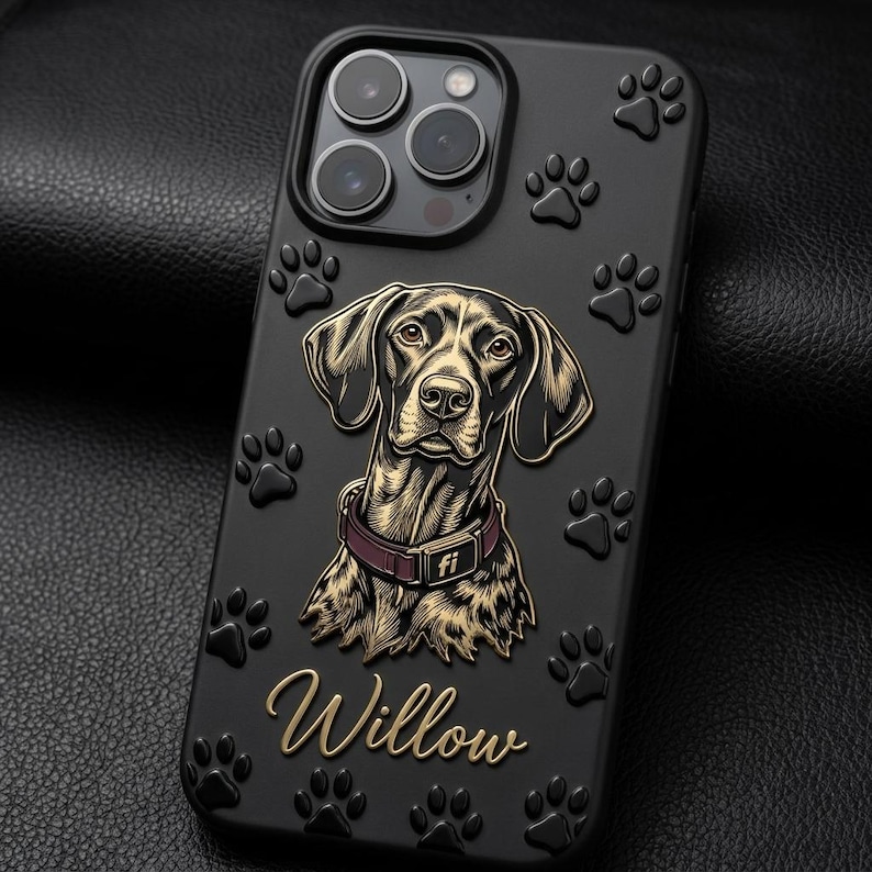 May include: A black smartphone case featuring a raised illustration of a brown dog wearing a purple collar with the text fi. The name Willow is written in gold script below the dog, and the case is decorated with embossed black paw prints.