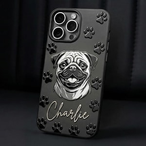 May include: A matte black smartphone case featuring a raised, monochromatic illustration of a pug's face in the center. The name Charlie is written in a white cursive script below the dog. The case is decorated with embossed paw prints.