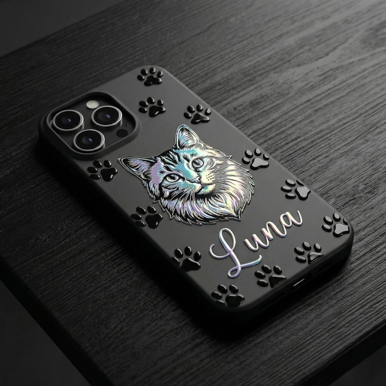 May include: A matte black smartphone case featuring a holographic illustration of a cat face centered on the back. The case is decorated with multiple raised black paw prints and the name Luna written in a white cursive script font.