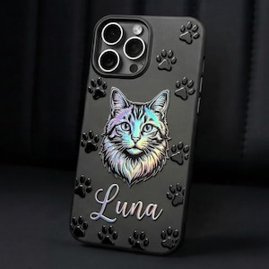 May include: A black smartphone case featuring a central iridescent cat face illustration and the name Luna in cursive script. The surface is decorated with embossed black paw prints surrounding the cat graphic and the camera lens cutout area.