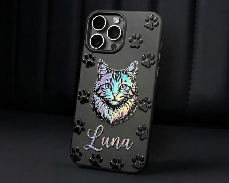 May include: A black smartphone case featuring a central iridescent cat face illustration and the name Luna in cursive script. The surface is decorated with embossed black paw prints surrounding the cat graphic and the camera lens cutout area.