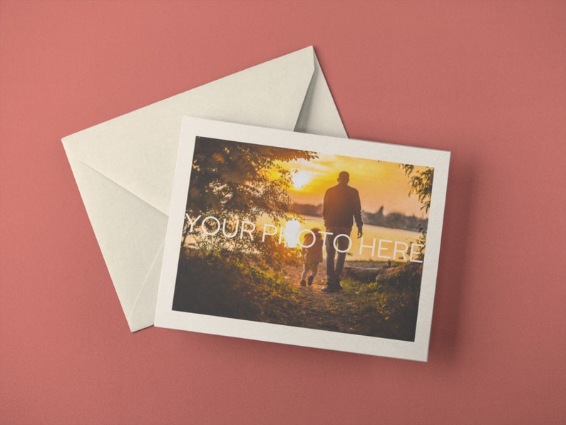 May include: A greeting card with a photograph of a person and child walking towards the sunset, with the text "YOUR PHOTO HERE". The card is accompanied by a cream-colored envelope, all set against a muted red background.