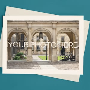 May include: A cream-colored card with the text "YOUR PHOTO HERE" overlaid on a photograph of an arched stone walkway. The card is on top of a cream-colored envelope, set against a teal background.