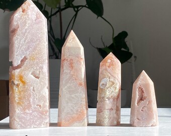 May include: Four pink and white agate crystal points, labeled A through D, arranged in a row on a white surface. The points are different sizes and have varying patterns of pink and white.