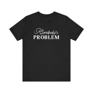May include: Black t-shirt with white text that reads "Somebody's PROBLEM" with a stylized cowboy hat graphic above the text.