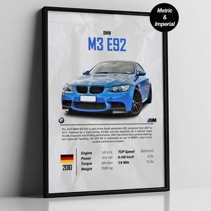 Puede incluir: Un póster enmarcado con un BMW M3 E92 azul. El póster incluye especificaciones técnicas como la cilindrada, la potencia, el par y el peso. El coche es de color azul brillante y el póster tiene un marco negro.