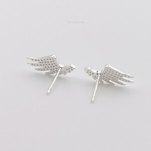 May include: A pair of silver wing-shaped earrings with a textured surface.