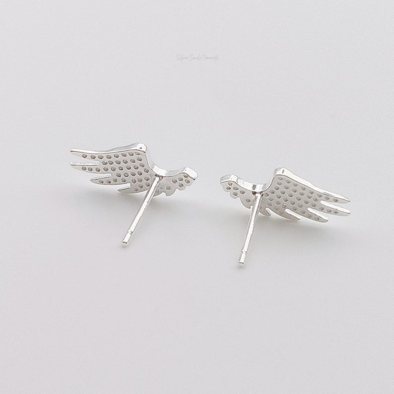 May include: A pair of silver wing-shaped earrings with a textured surface.