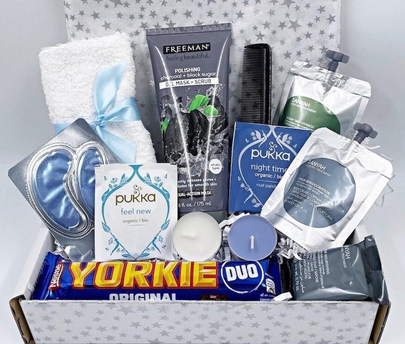 Pu&ograve; includere: Una scatola regalo contenente un asciugamano bianco con un nastro blu, una maschera in gel al carbone Freeman, un pettine nero, due bustine di t&egrave; Pukka, due bustine in alluminio, due piccole candele rotonde, una barretta di cioccolato Yorkie e un sapone grigio.