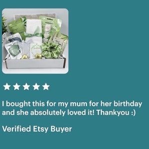 May include: A white gift box filled with green and white bath and body products. The box includes a white towel, a green headband, a green bath bomb, and a green face mask. The box is labeled "Mud".