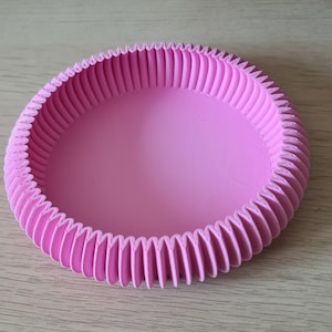 Könnte beinhalten: Eine runde, rosa Schale aus dem 3D-Druck mit geriffeltem Design. Die Schale hat einen glatten, abgerundeten Innenraum und eine strukturierte Außenseite.