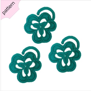 May include: Three teal crocheted flower shapes with a centre hole. The flowers are made with a single crochet stitch and have a delicate, lacy appearance.