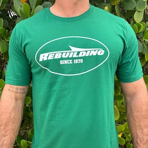 May include: A green t-shirt with a white oval logo that says "REBUILDING SINCE 1970".