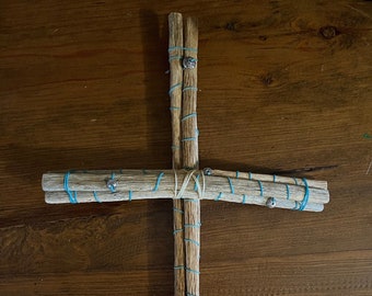 May include: A wooden cross made of multiple sticks tied together with blue string and decorated with silver beads.