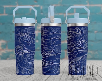 May include: A blue stainless steel tumbler with a white design of whales, waves, and seashells. The tumbler has a blue lid and a blue handle.