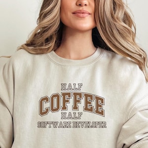 May include: A beige sweatshirt with the text "Half Coffee Half Software Developer" in brown lettering.