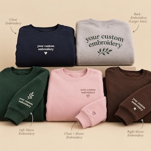 Könnte beinhalten: Fünf Rundhals-Sweatshirts in Marineblau, Hellgrau, Dunkelgrün, Hellrosa und Braun. Jedes zeigt den gestickten Text your custom embroidery mit verschiedenen Symbolen wie Herzen, Blättern und Sternen auf der Brust, dem Ärmel oder dem Rücken.