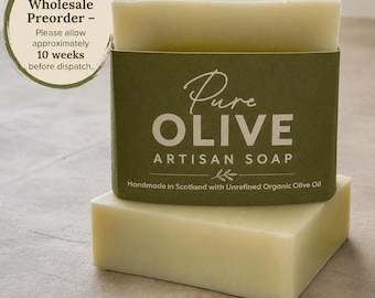 May include: A rectangular bar of pale green artisan soap wrapped in a dark olive green paper band. The label reads Pure OLIVE ARTISAN SOAP, Handmade in Scotland with Unrefined Organic Olive Oil. A circular badge notes Wholesale Preorder.