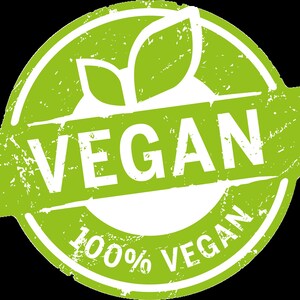 May include: A circular green and white emblem featuring a distressed texture. The design includes two stylized leaves at the top and a central horizontal banner with the word VEGAN in bold white capital letters. The text 100% VEGAN is printed below.