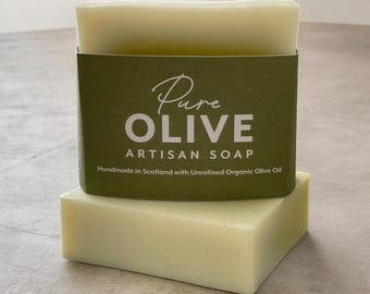 May include: A rectangular bar of pale green soap wrapped in a dark olive green paper band. The label features the white text Pure OLIVE ARTISAN SOAP and the smaller text Handmade in Scotland with Unrefined Organic Olive Oil.