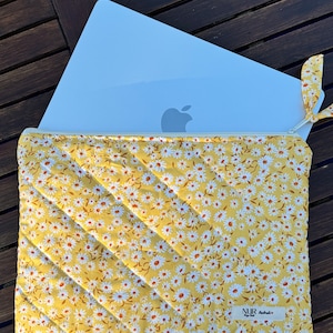 Może przedstawiać: Żółta torba na laptopa z nadrukiem białych stokrotek. Torba ma zamek błyskawiczny i małą etykietę z napisem "NUR Handmade".