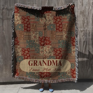 Könnte beinhalten: Eine Patchwork-Wurfdecke mit Fransen. Die Decke zeigt verschiedene Blumen- und Streifenmuster in Rot, Blau und Beige. Das Wort "GRANDMA" wird in einem Banner mit Namen darunter angezeigt.