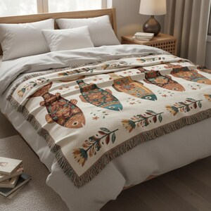 May include: A beige throw blanket with a repeating pattern of colorful, stylized fish. The fish are decorated with floral and geometric designs in shades of orange, blue, and green. The blanket has a fringed edge.