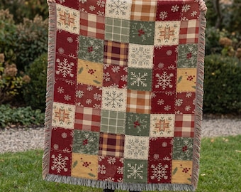 Könnte beinhalten: Eine gewebte Wohndecke mit einem Patchwork-Design aus abwechselnden Quadraten. Das Muster umfasst rot-weißes Karomuster, grüne Quadrate mit roten Beeren und cremefarbene Quadrate mit weißen Schneeflockenmotiven. Die Ränder haben einen Fransenabschluss.