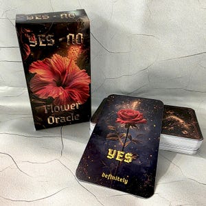 Puede incluir: Una baraja de cartas Flower Oracle con una caja negra con una flor de hibisco roja. Las cartas tienen un fondo oscuro con una rosa roja y la palabra "YES" en dorado. También se ven las palabras "YES - NO" y "Flower Oracle".