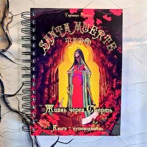 May include: A spiral-bound book titled Santa Muerte Tarot with a cover illustration of a skeletal figure in a red robe and green cloak standing in a doorway. The cover features red floral accents, a yellow sun, and Russian text including Жизнь через Смерть.