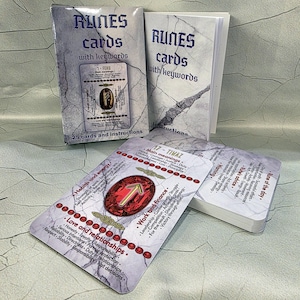 May include: A set of rune cards with keywords, featuring a marble-textured design. The cards display symbols and text, including "Runes cards with keywords" and "25 cards and instructions." The cards are for divination and spiritual guidance.